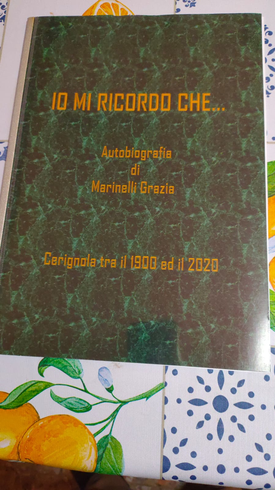 Copertina del libro "Io mi ricordo che...", autobiografia di Marinelli Grazia. Il volume, che narra le vicende di Cerignola tra il 1900 e il 2020, presenta una copertina con sfondo marmorizzato verde scuro e scritte in caratteri arancioni.